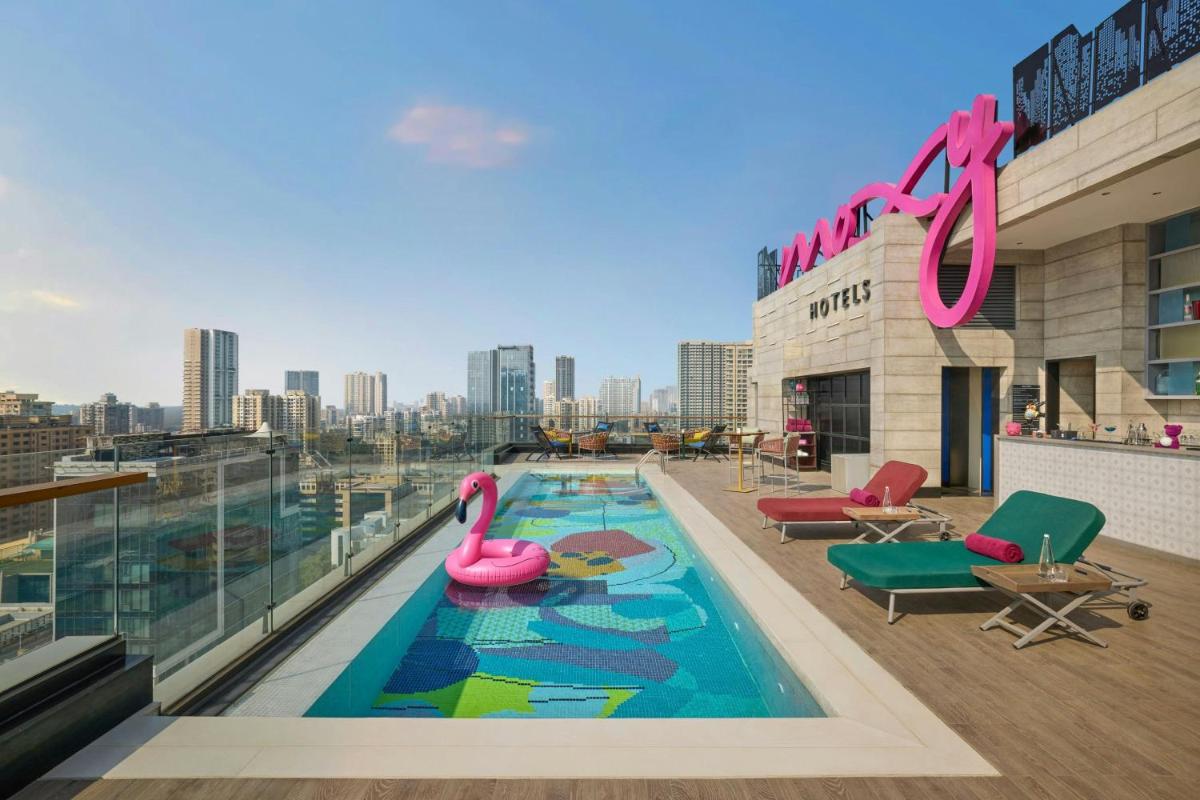 a swimming pool with pink flamingos on the roof of a building at Moxy Mumbai Andheri West in Mumbai