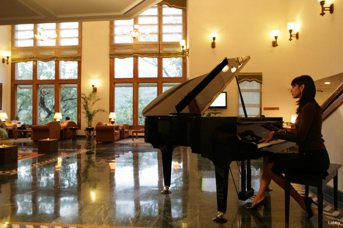 a woman sitting at a piano in a room at Jaypee Residency Manor in Mussoorie