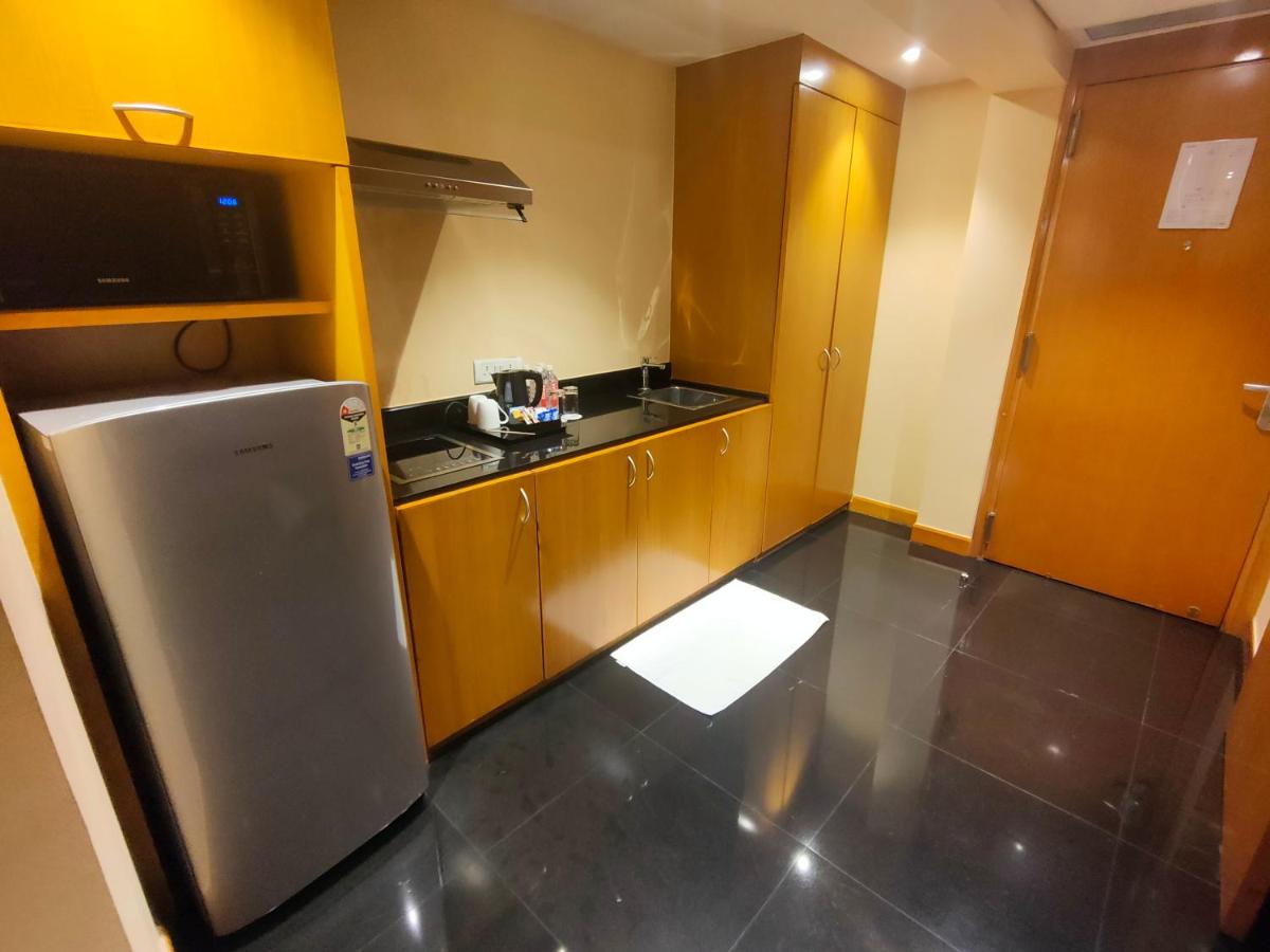 a small kitchen with a refrigerator and wooden cabinets at The Grand New Delhi in New Delhi a small kitchen with a refrigerator and wooden cabinets at The Grand New Delhi in New Delhi