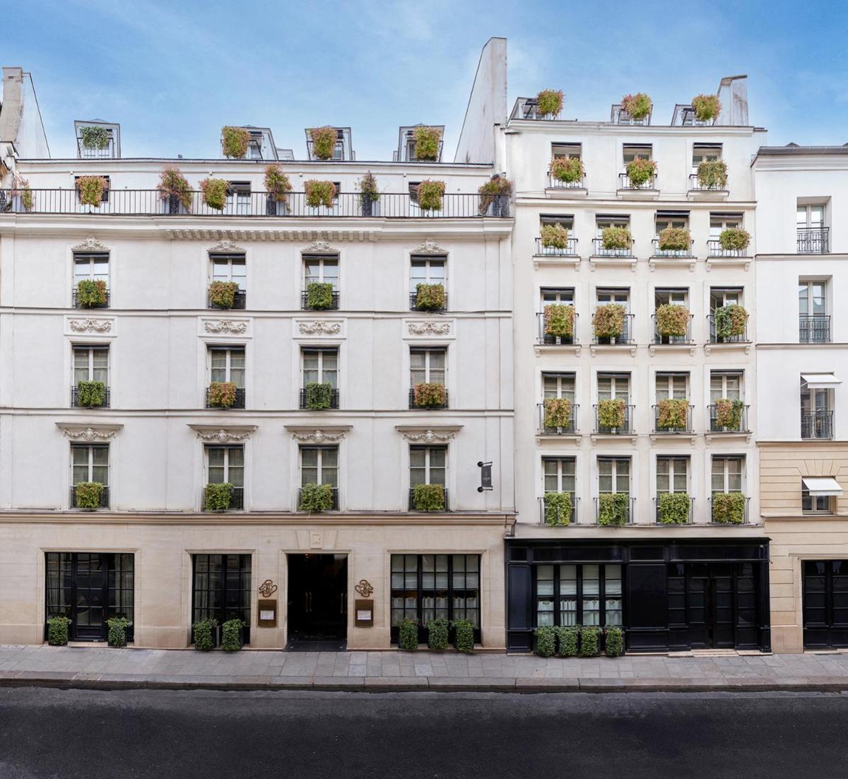 un bâtiment blanc avec des plantes en pot aux fenêtres dans l'établissement Le Burgundy Paris, à Paris