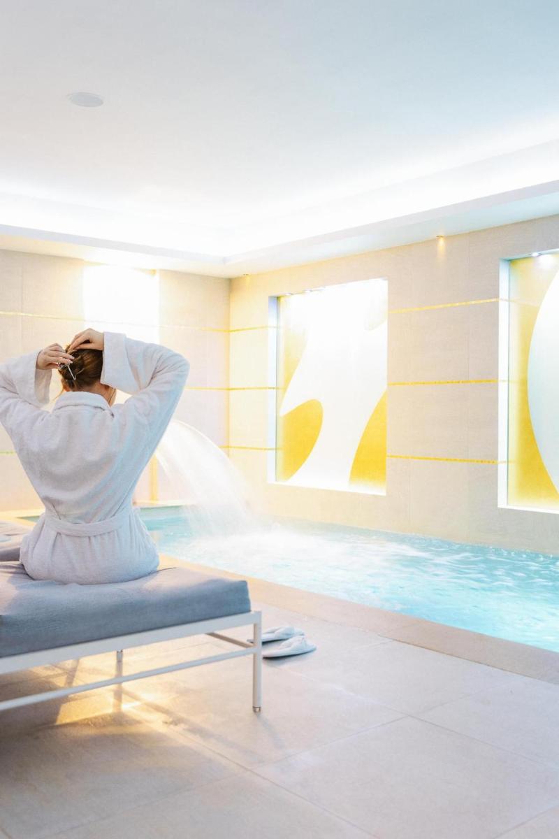 une femme assise sur une chaise devant une piscine dans l'établissement Le Burgundy Paris, à Paris