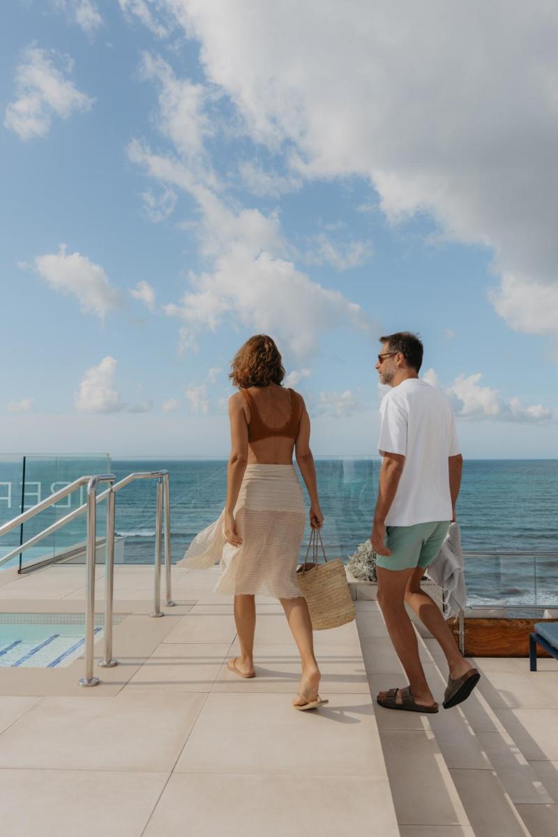 un hombre y una mujer caminando en un muelle cerca del océano en Iberostar Waves Bahía de Palma - Adults Only, en Playa de Palma