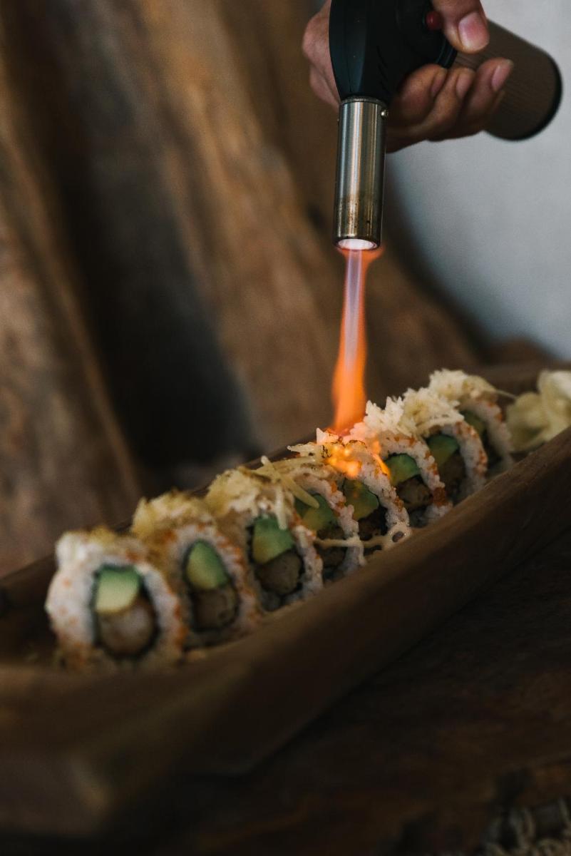 una persona está usando una cuchara para poner sushi en una mesa en Iberostar Waves Bahía de Palma - Adults Only, en Playa de Palma