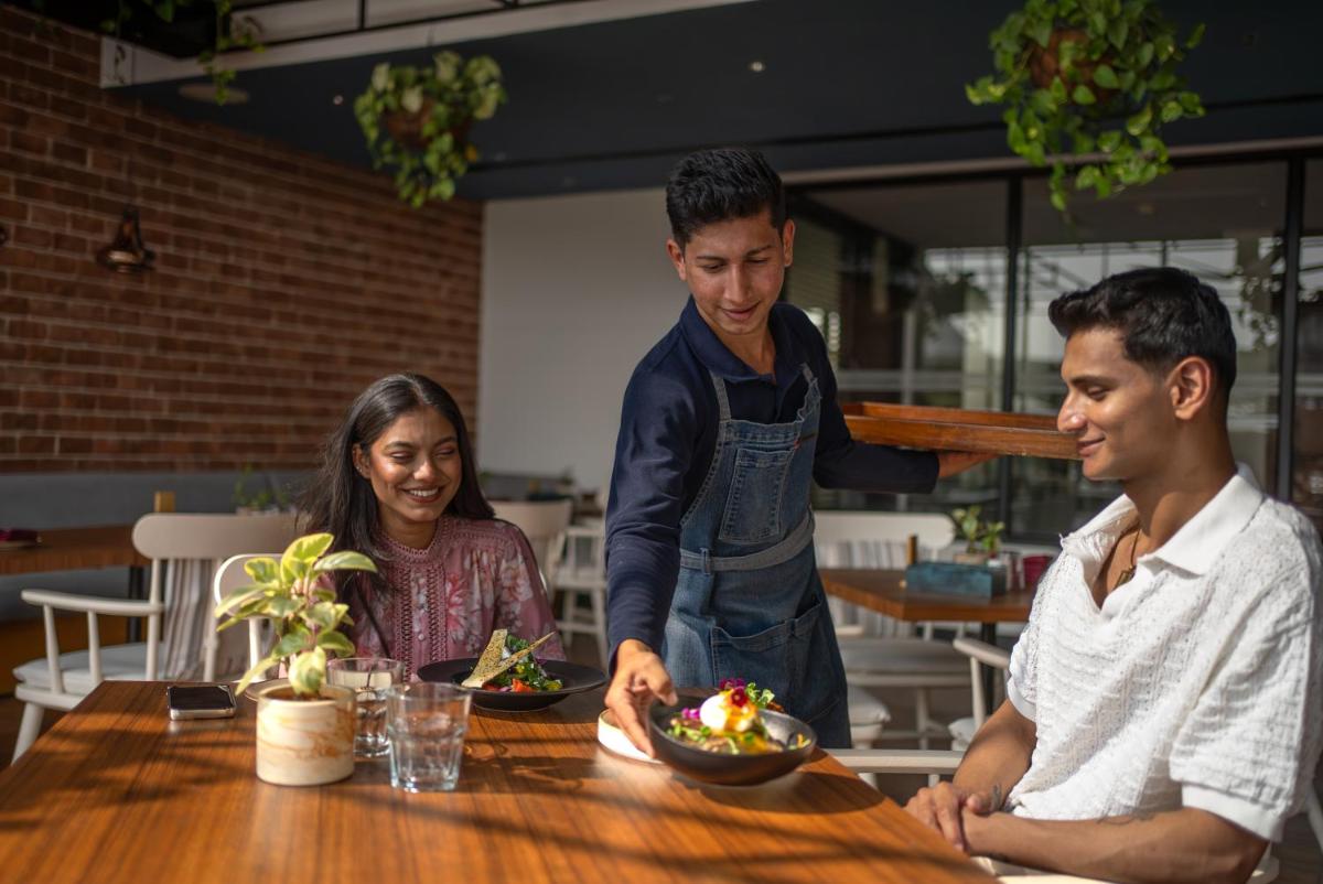 a man presenting a plate of food to two people at a table at Hyatt Centric MG Road Bangalore in Bengaluru a man presenting a plate of food to two people at a table at Hyatt Centric MG Road Bangalore in Bengaluru