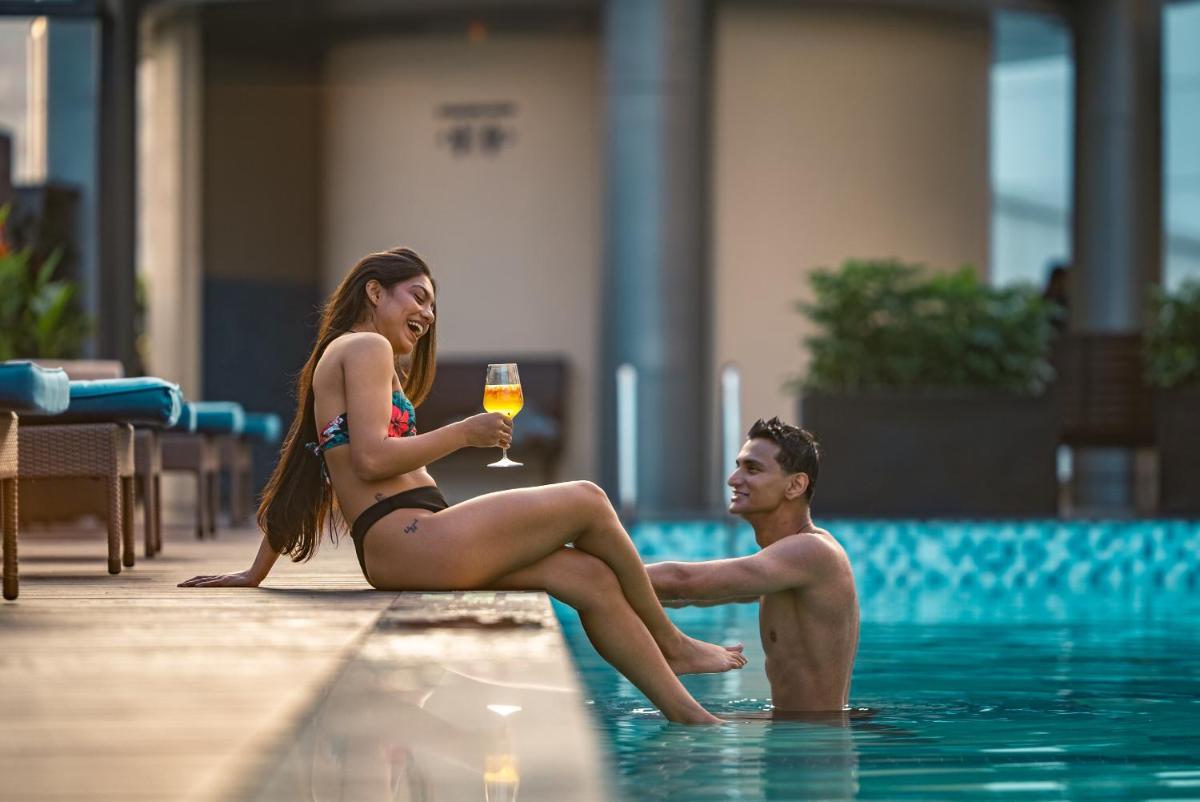 a man and woman sitting in the swimming pool with a glass of wine at Hyatt Centric MG Road Bangalore in Bengaluru a man and woman sitting in the swimming pool with a glass of wine at Hyatt Centric MG Road Bangalore in Bengaluru