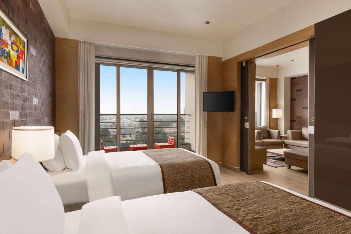a hotel room with two beds and a television at Wyndham Ahmedabad Shela in Ahmedabad