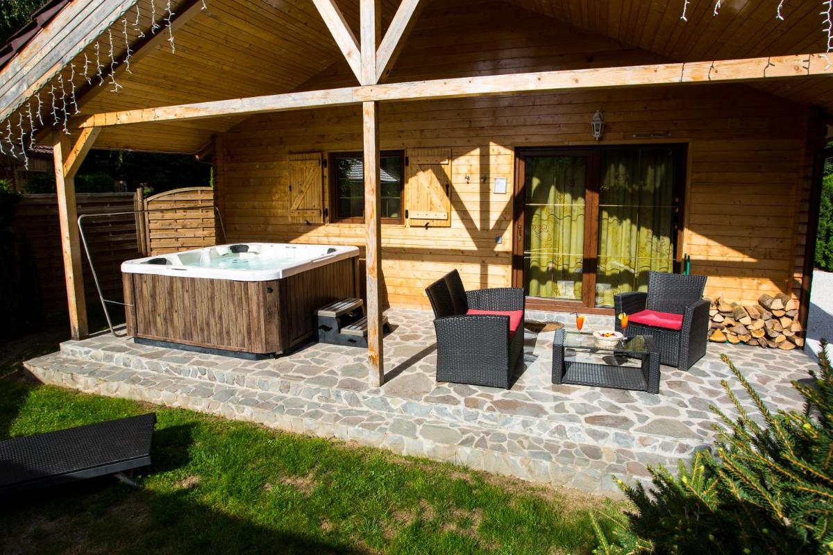 d'une terrasse avec un bain à remous et des chaises. dans l'établissement Domaine du Haut Jardin Hôtel & Chalets Spa Privé, à Rehaupal