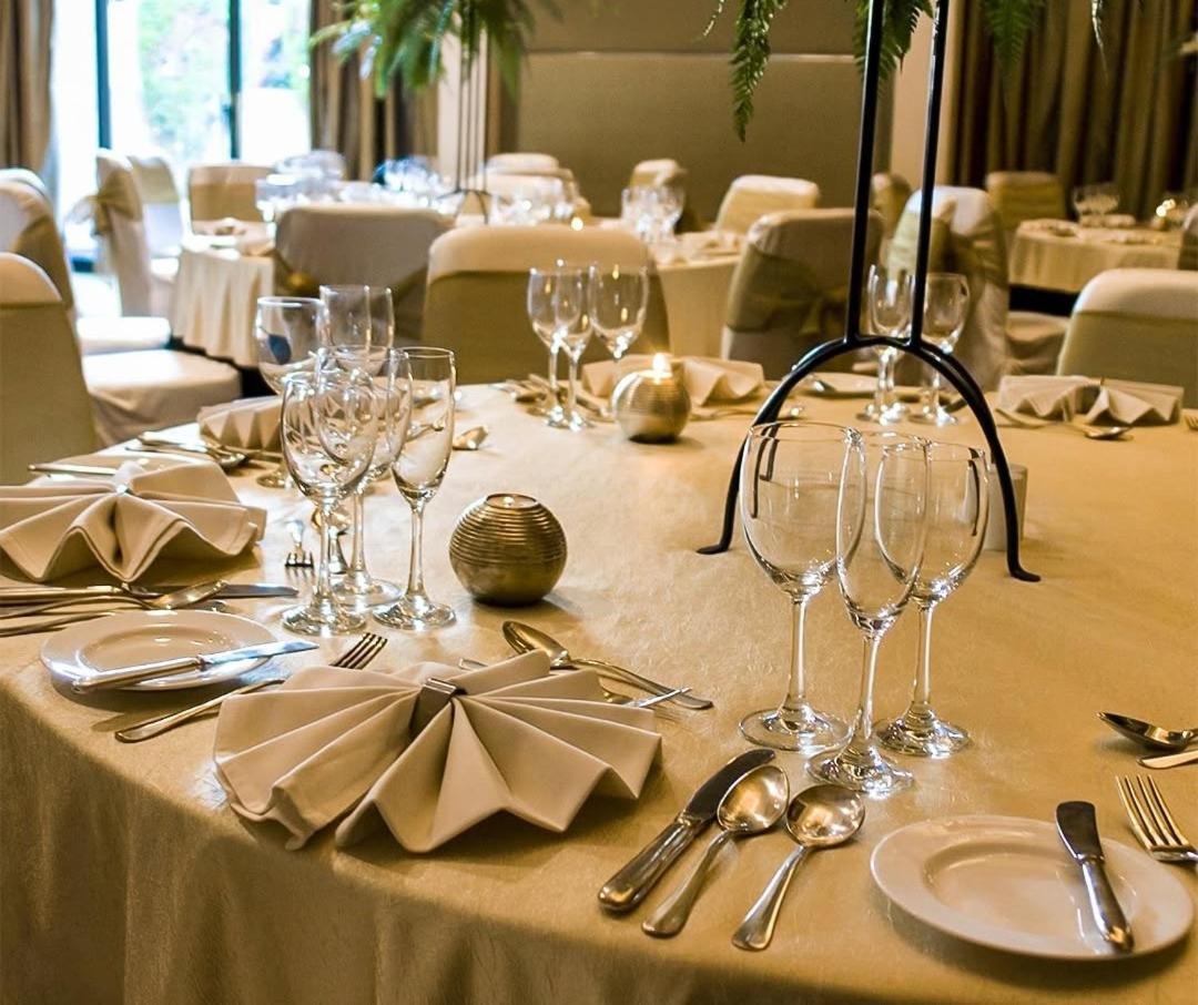a table with wine glasses and silverware on it at The Grand New Delhi in New Delhi a table with wine glasses and silverware on it at The Grand New Delhi in New Delhi