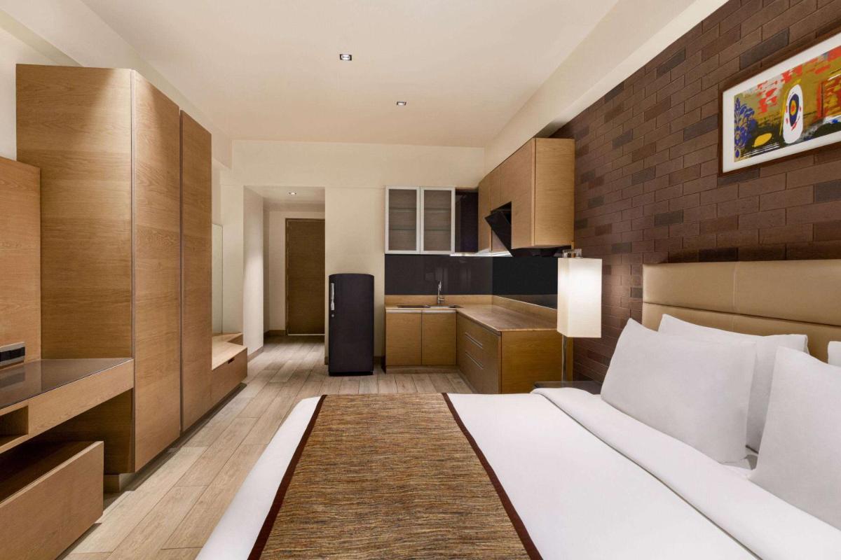 a hotel room with a large bed and a kitchen at Wyndham Ahmedabad Shela in Ahmedabad