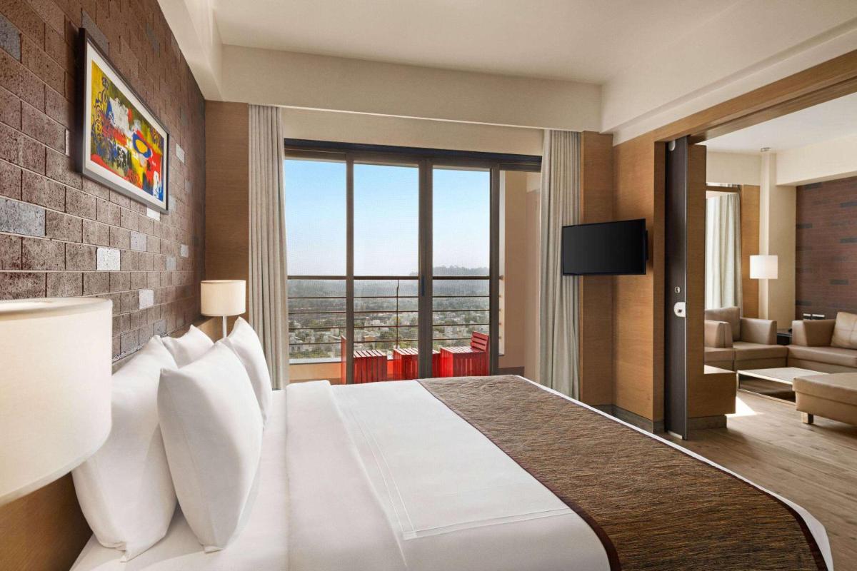 a hotel room with a bed and a living room at Wyndham Ahmedabad Shela in Ahmedabad