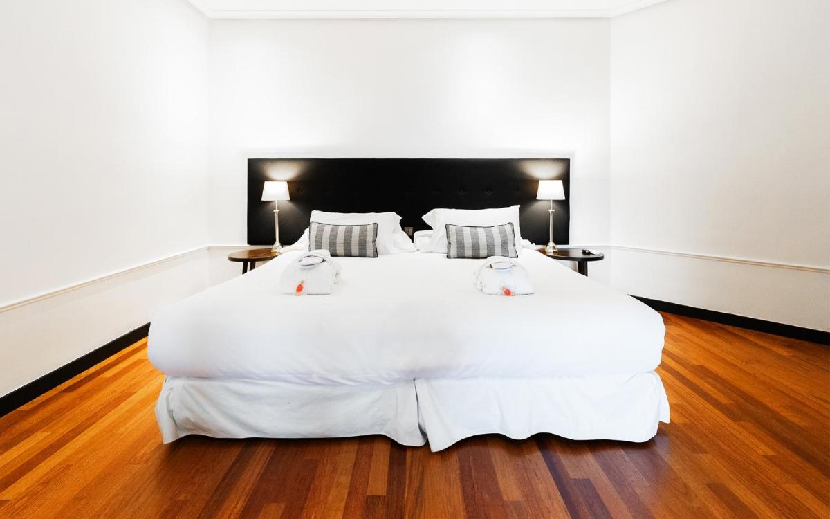 Un dormitorio con una gran cama blanca con dos almohadas. en Hotel Hita "Nature Experience" for all, en Navacerrada
