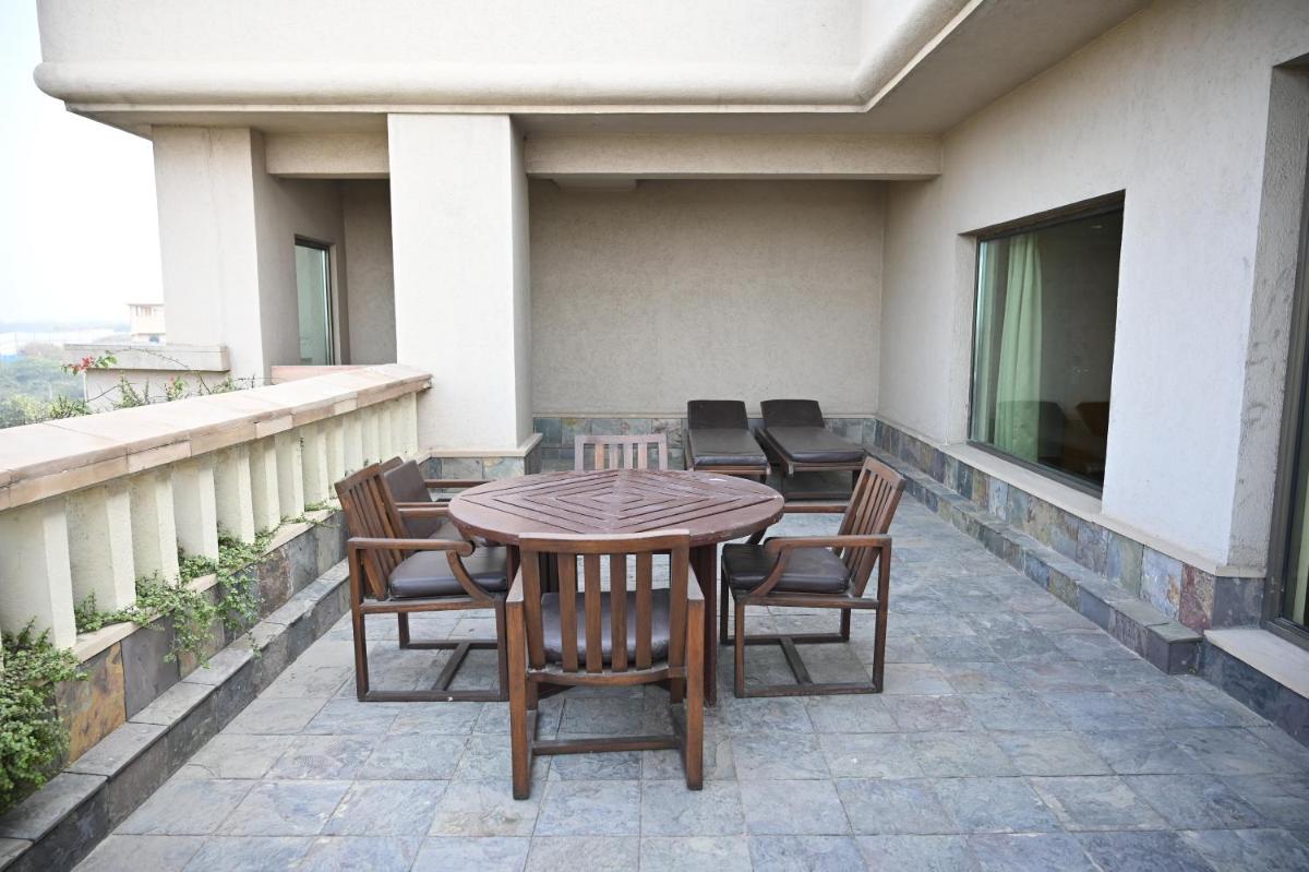 a patio with a table and chairs on a balcony at The Grand New Delhi in New Delhi a patio with a table and chairs on a balcony at The Grand New Delhi in New Delhi