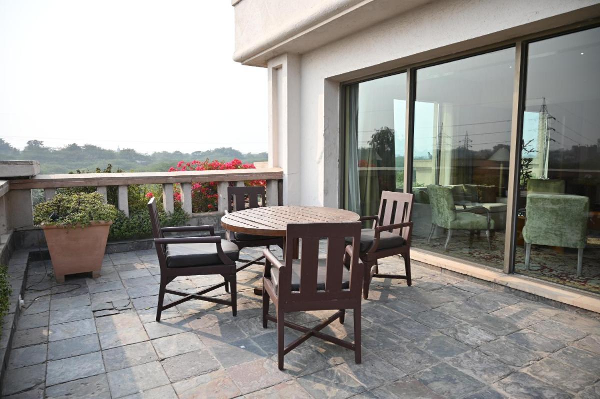 a wooden table and chairs on a patio at The Grand New Delhi in New Delhi a wooden table and chairs on a patio at The Grand New Delhi in New Delhi