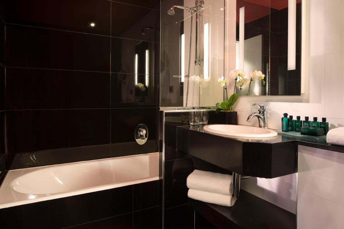 La salle de bains en noir et blanc est pourvue d'un lavabo et d'une baignoire. dans l'établissement Le Belmont Paris, à Paris