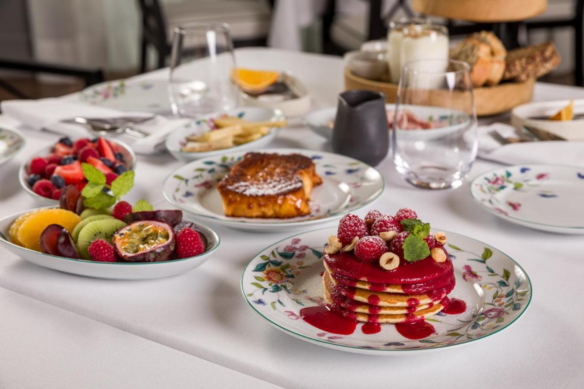 uma mesa com pratos de comida e frutas sobre ela em Amoure Hotel - The Leading Hotels of the World em Braga