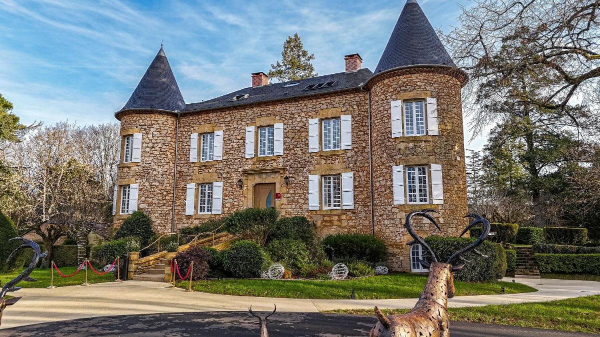 un grand bâtiment en briques avec deux tours au sommet dans l'établissement Château de Maraval, à Cénac-et-Saint-Julien