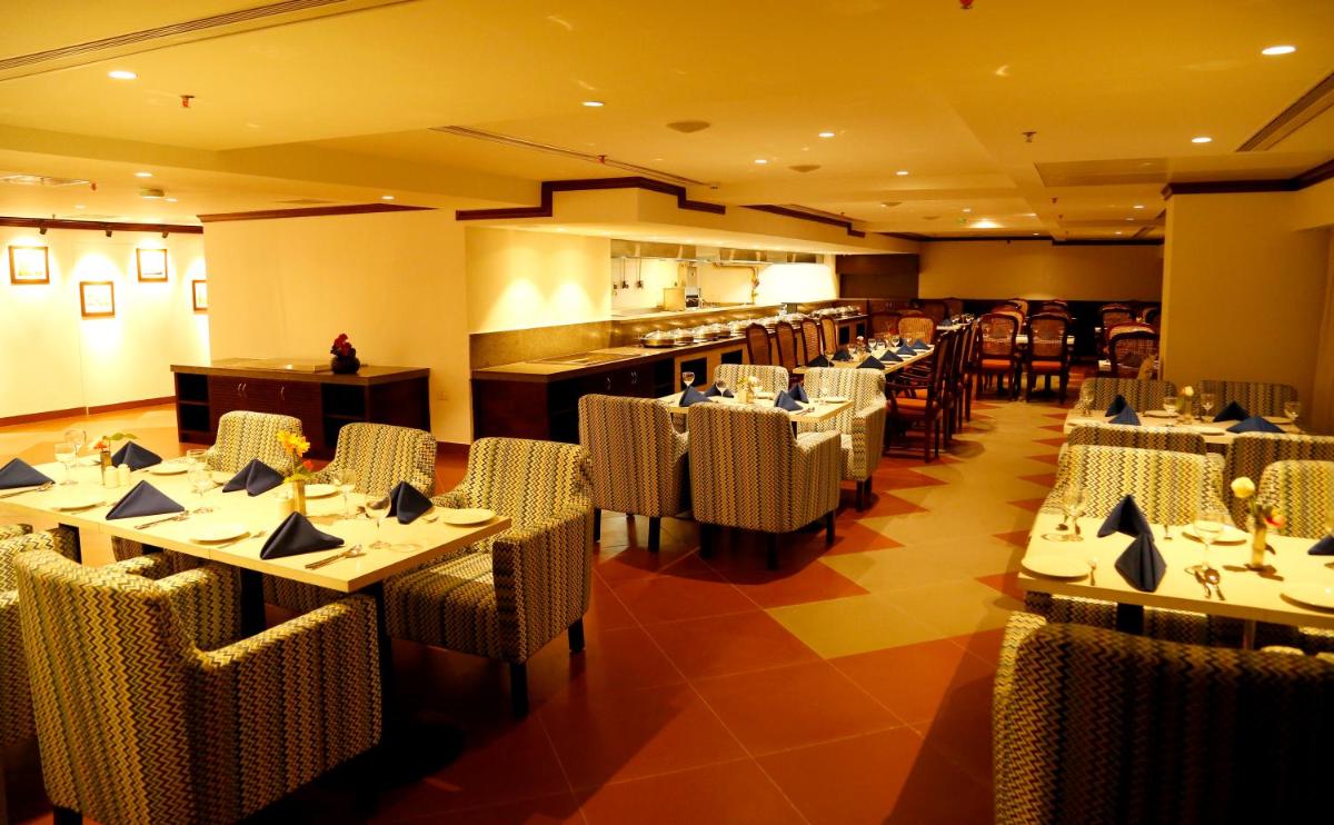 a restaurant with tables and chairs and a kitchen at The Raviz Calicut in Kozhikode