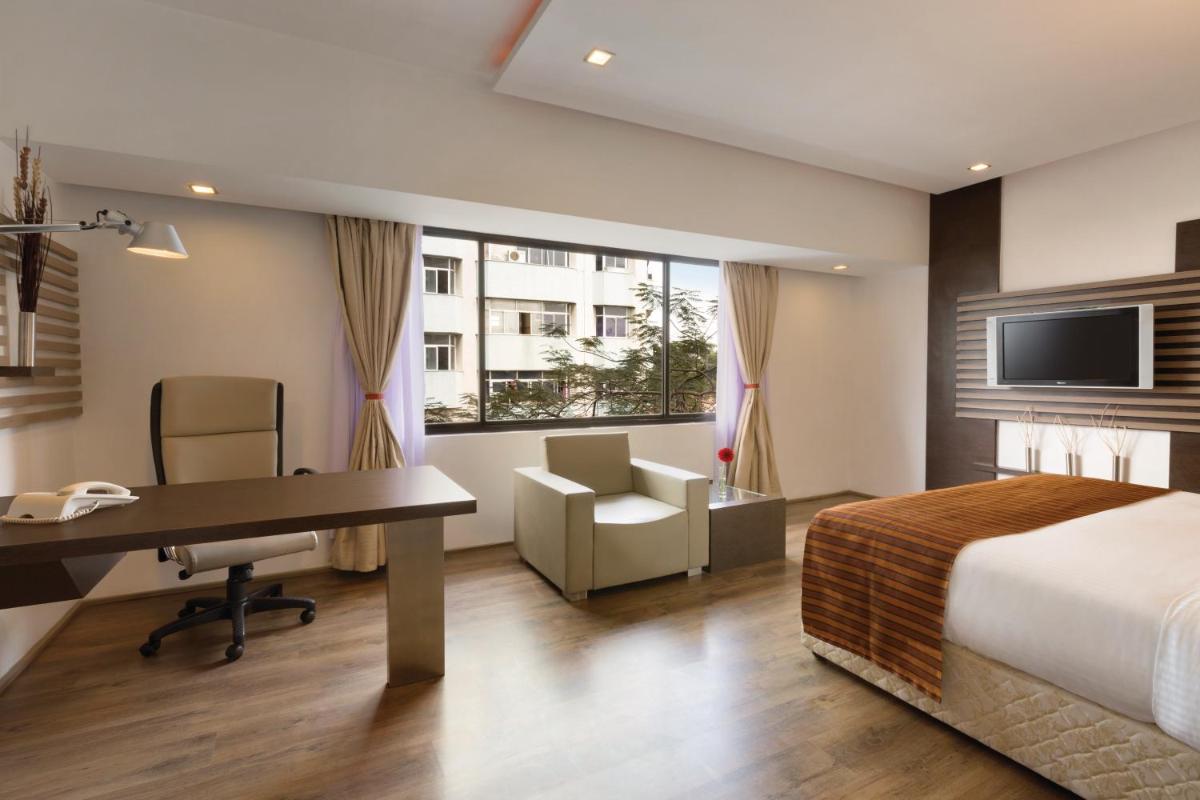 a hotel room with a bed and a desk and a computer at Ramada by Wyndham Chennai Egmore in Chennai a hotel room with a bed and a desk and a computer at Ramada by Wyndham Chennai Egmore in Chennai