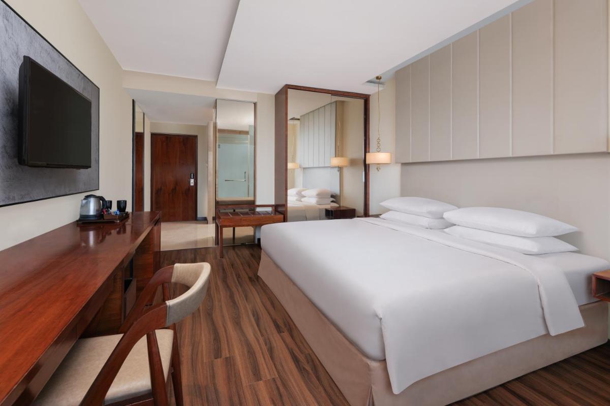 a bedroom with a large white bed and a television at Renaissance Ahmedabad Hotel in Ahmedabad