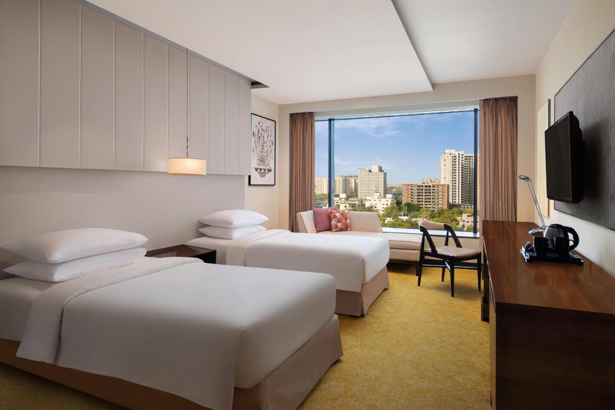 a hotel room with two beds and a window at Renaissance Ahmedabad Hotel in Ahmedabad