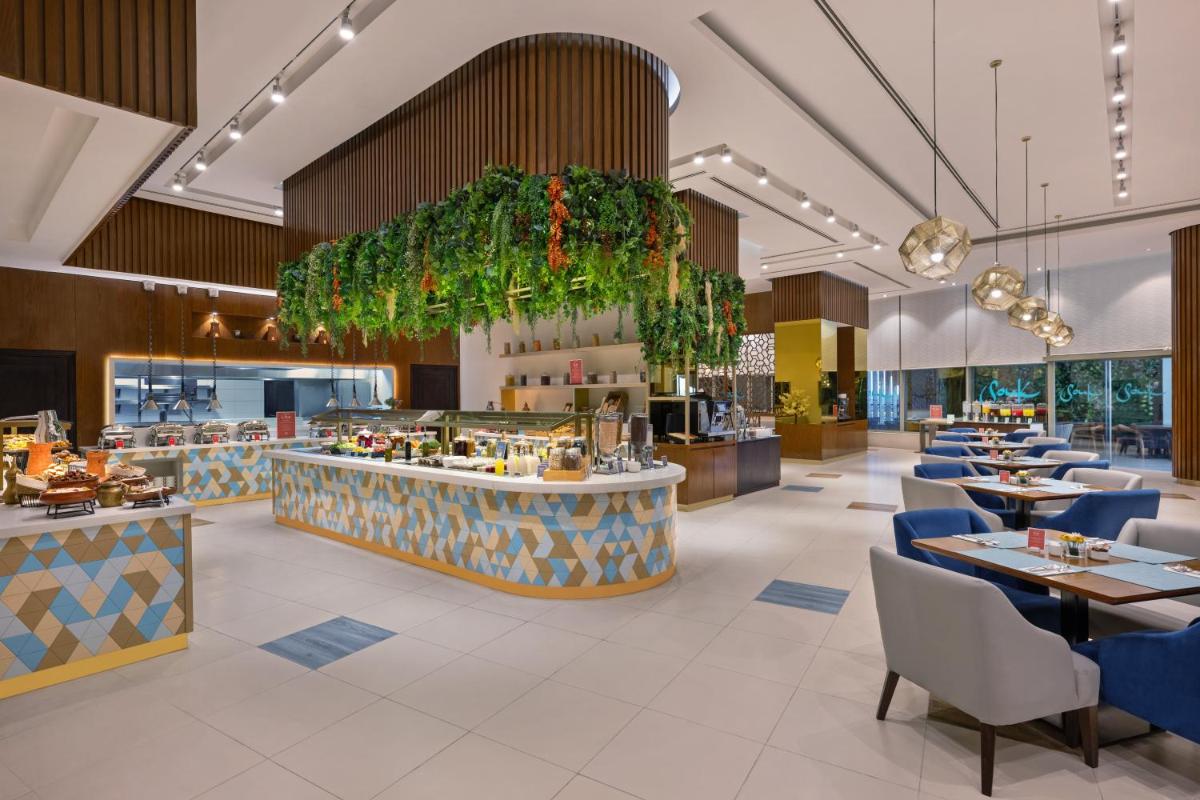 a restaurant with tables and chairs and a bar at Barcelo Al Jaddaf, Dubai in Dubai