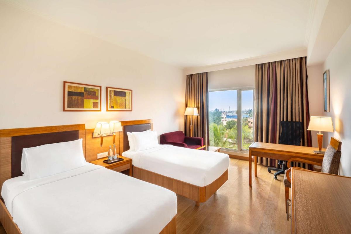 a hotel room with two beds and a desk at Park Plaza Chennai OMR in Chennai