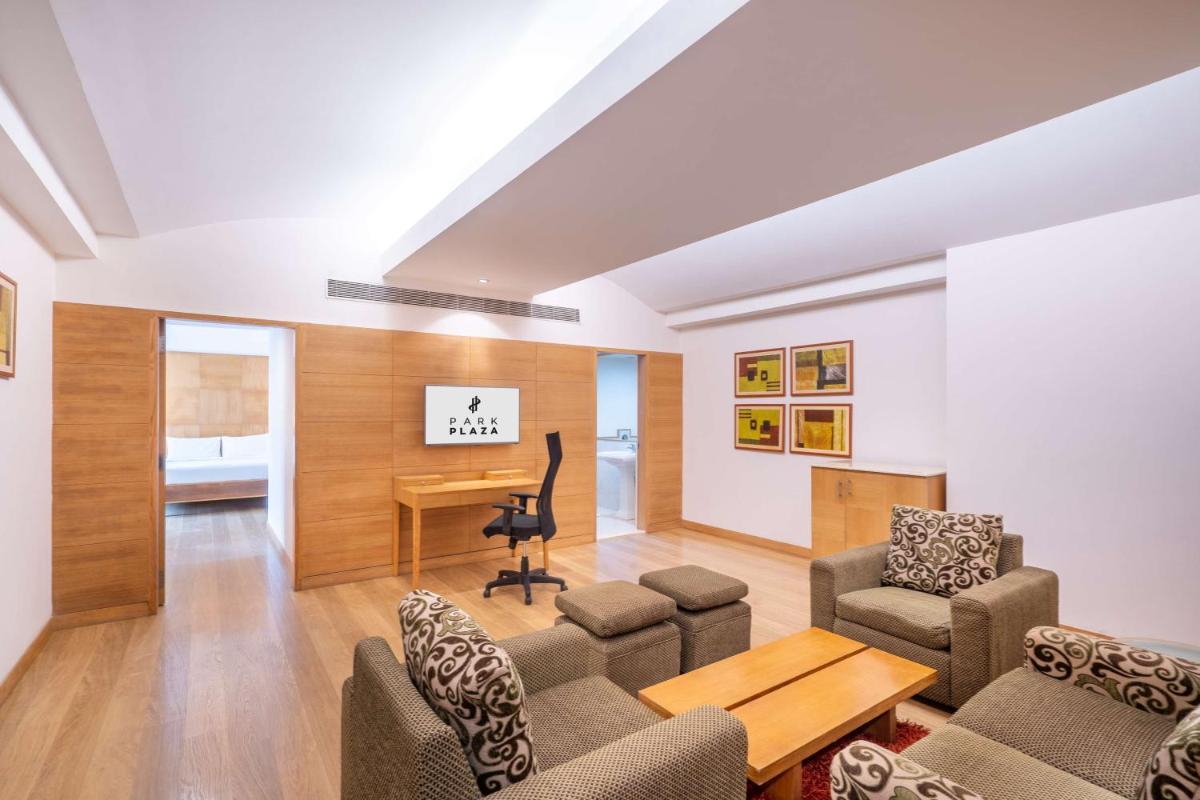 a living room with a table and chairs and a desk at Park Plaza Chennai OMR in Chennai