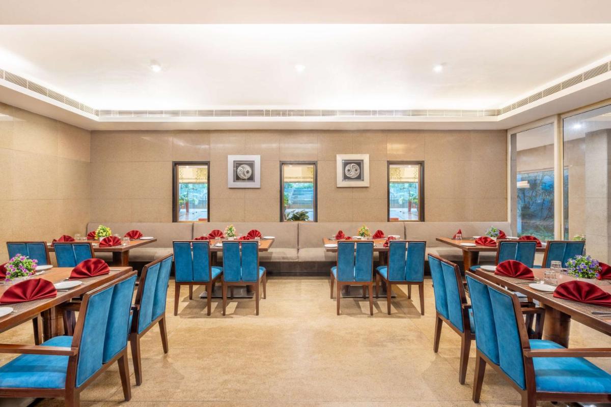 a large dining room with tables and blue chairs at Park Plaza Chennai OMR in Chennai