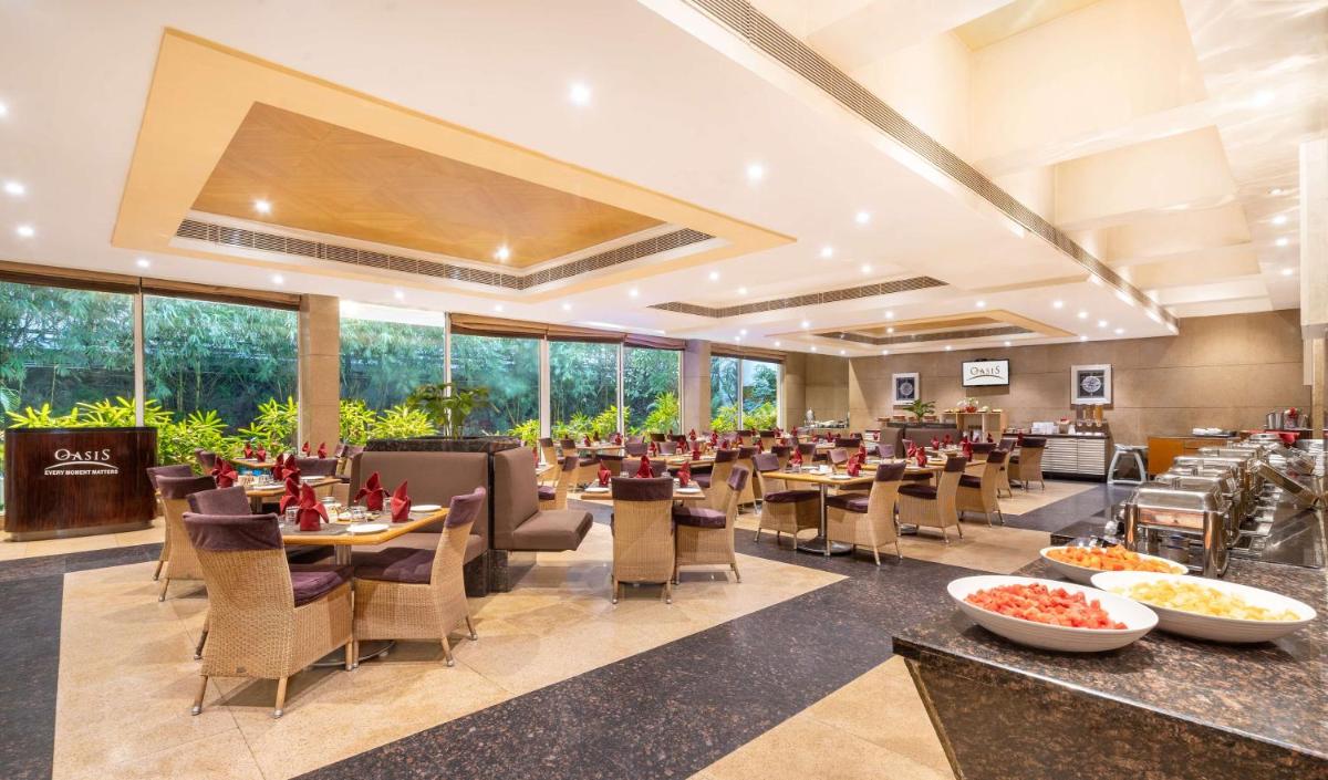 a restaurant with tables and chairs and windows at Park Plaza Chennai OMR in Chennai