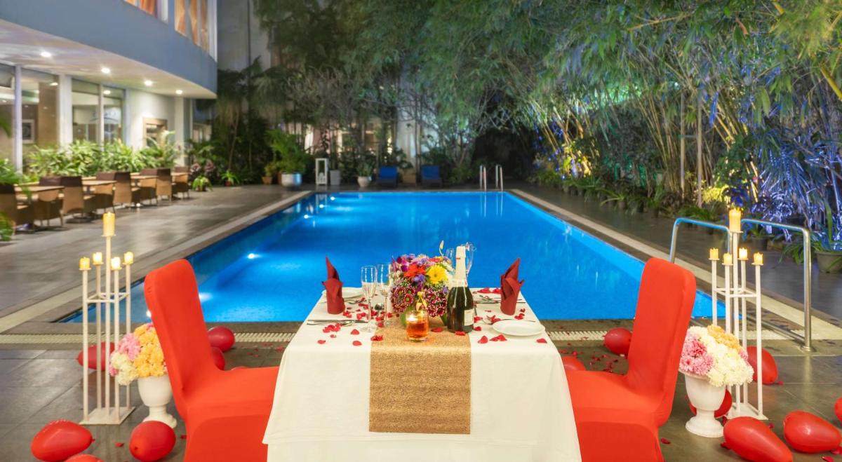 a dining table in front of a swimming pool at Park Plaza Chennai OMR in Chennai