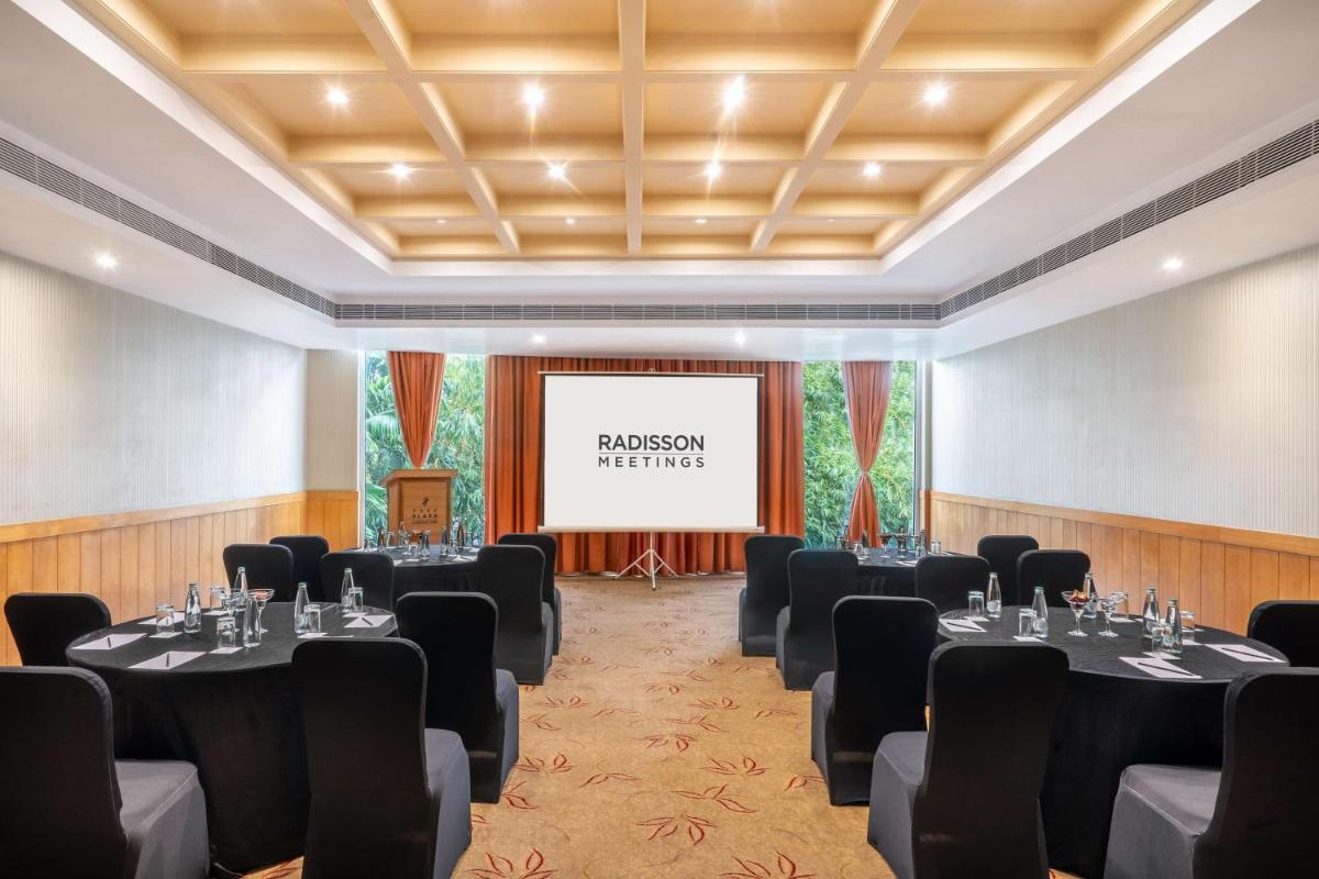 a conference room with tables and chairs and a screen at Park Plaza Chennai OMR in Chennai