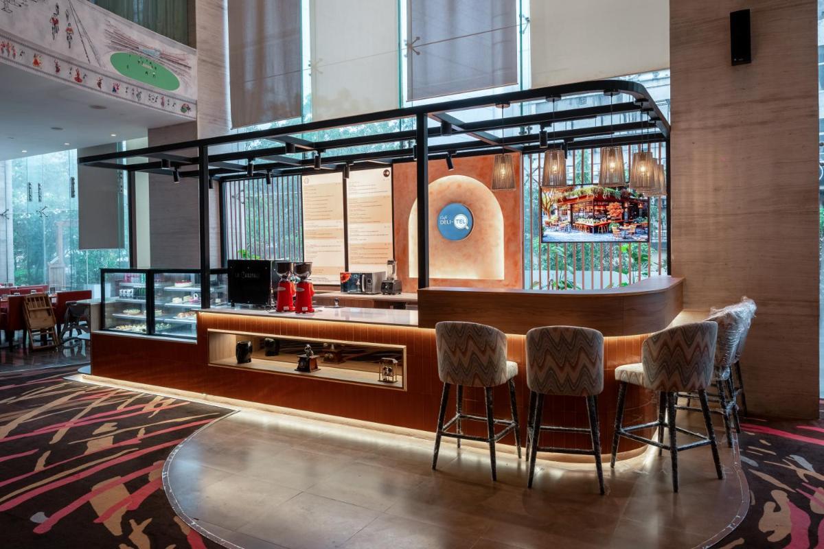a bar in a restaurant with stools at Novotel Ahmedabad in Ahmedabad