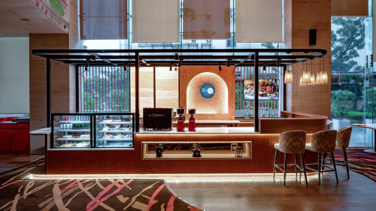a restaurant with a bar with chairs and a counter at Novotel Ahmedabad in Ahmedabad