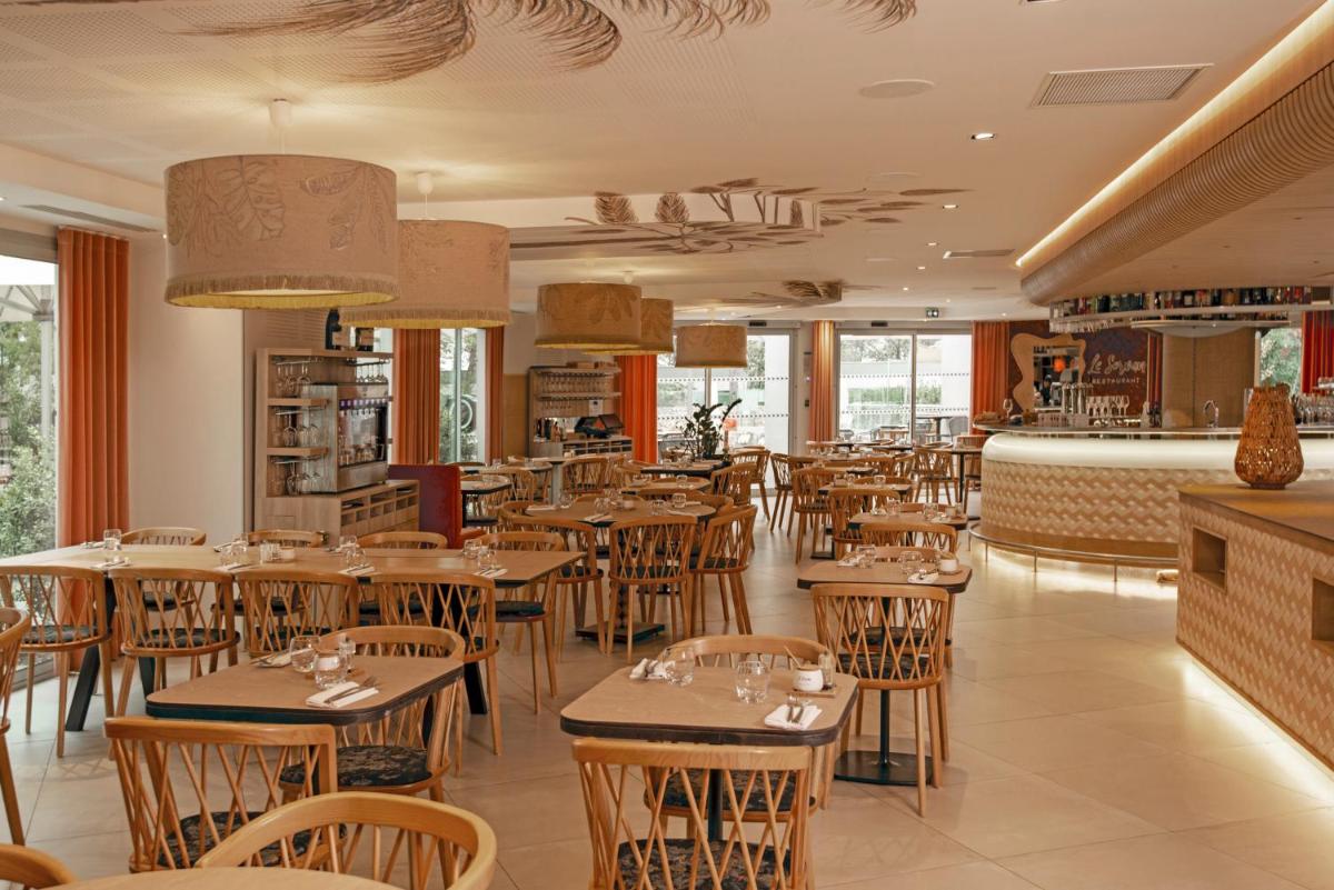 un restaurant avec des tables et des chaises en bois dans l'établissement Golden Tulip Sophia Antipolis - Hotel & Spa, à Valbonne
