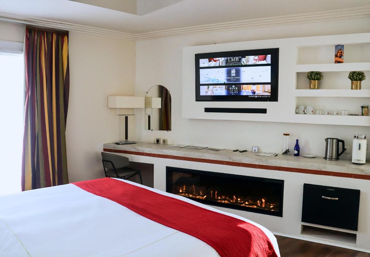 Cette chambre d'hôtel dispose d'une cheminée et d'une télévision. dans l'établissement Grand Tonic Hotel & SPA NUXE, à Biarritz