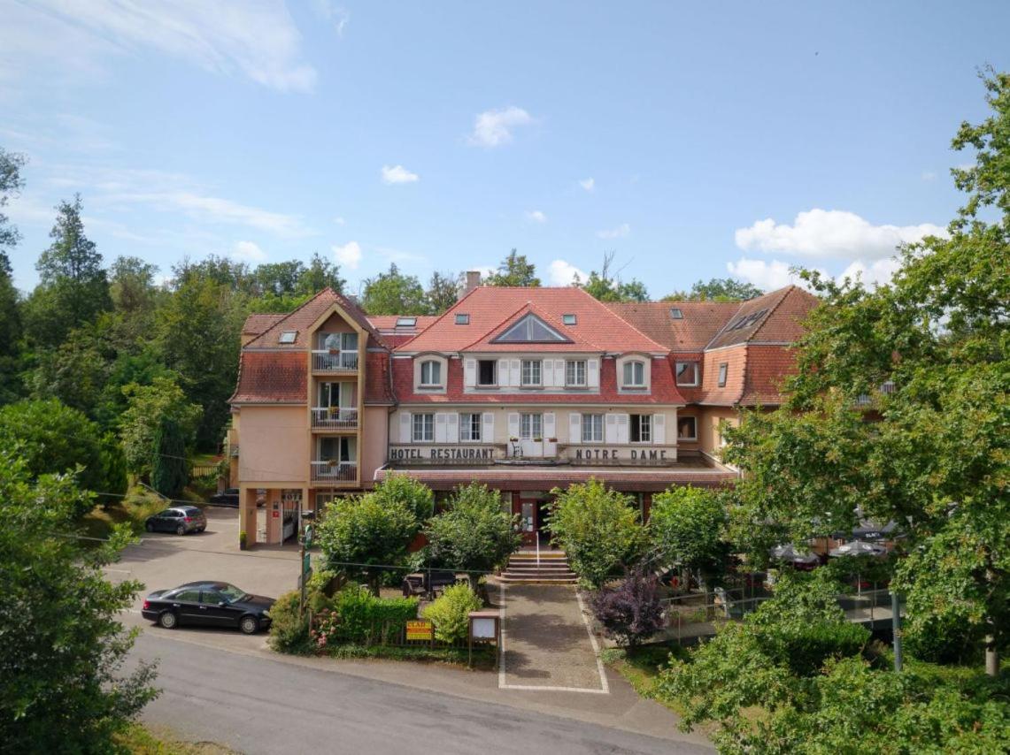 une grande maison avec une voiture garée dans un parking dans l'établissement Logis Hôtel Notre-Dame - restaurant ouvert midi et soir sauf dimanche soir, à Danne-et-Quatre-Vents