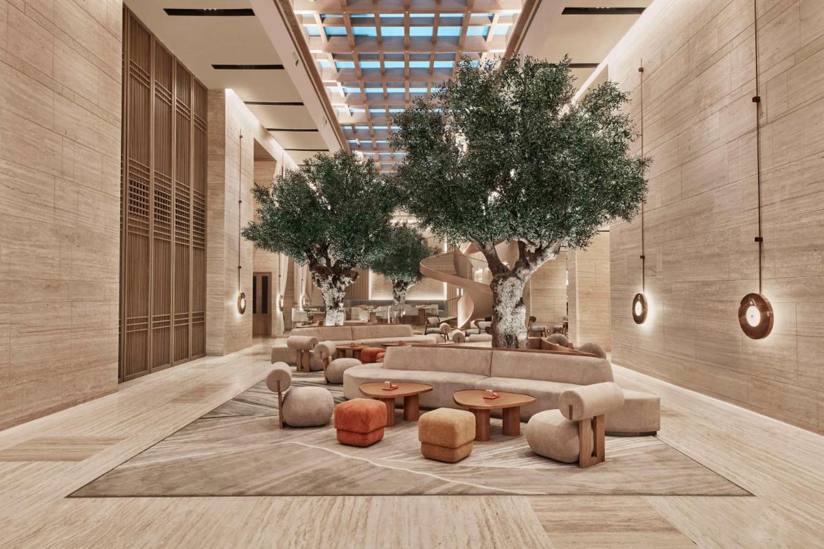 a lobby with couches and tables and trees at Hilton Gurugram Baani City Centre in Gurgaon