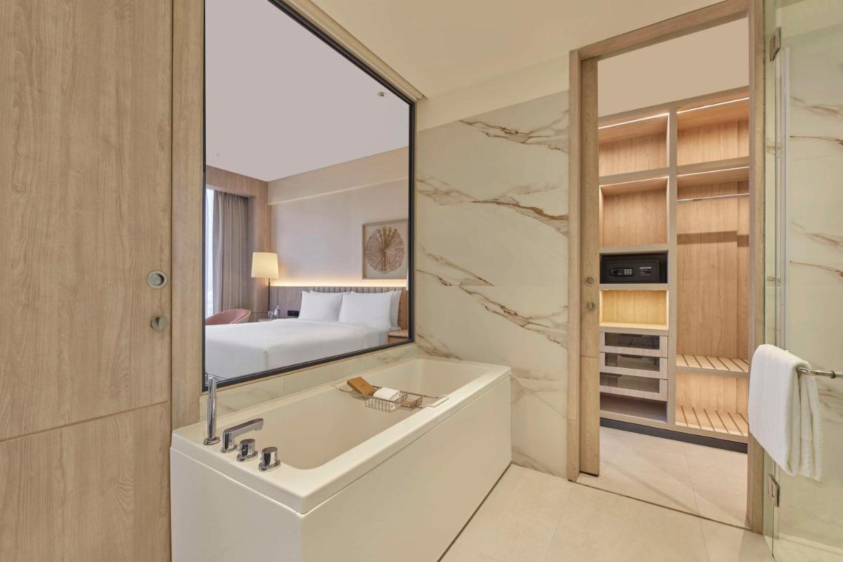 a bathroom with a tub and a bedroom with a bed at Hilton Gurugram Baani City Centre in Gurgaon