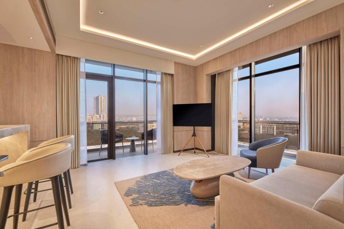 a living room with a couch and chairs and windows at Hilton Gurugram Baani City Centre in Gurgaon