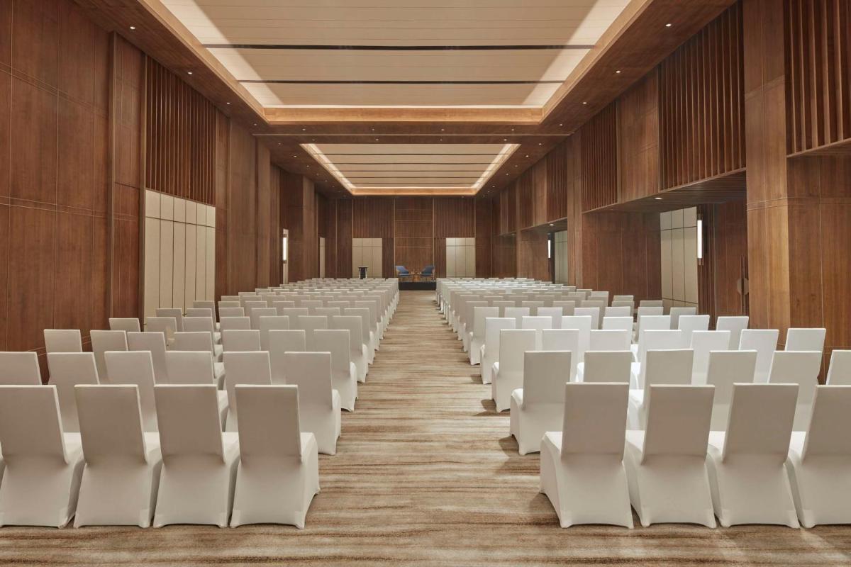 an empty lecture hall with white chairs and wooden walls at Hilton Gurugram Baani City Centre in Gurgaon