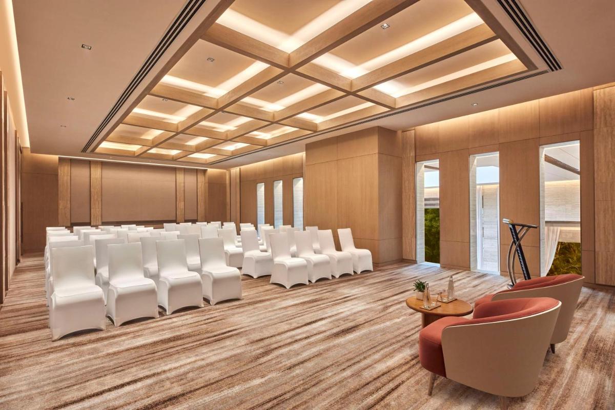 a conference room with white chairs and a podium at Hilton Gurugram Baani City Centre in Gurgaon
