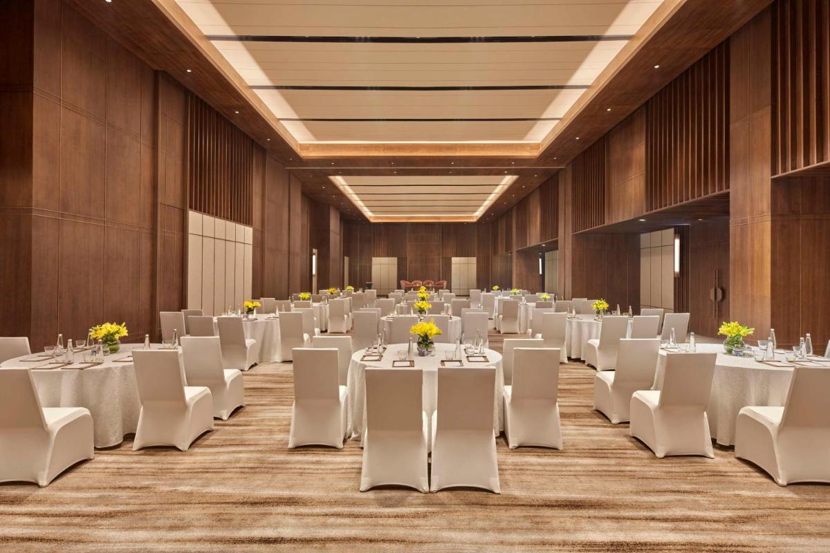 a banquet hall with white tables and white chairs at Hilton Gurugram Baani City Centre in Gurgaon