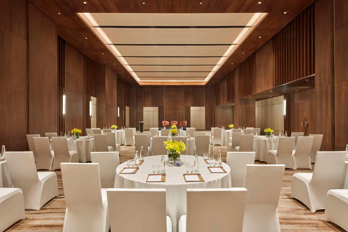 a banquet hall with white tables and white chairs at Hilton Gurugram Baani City Centre in Gurgaon