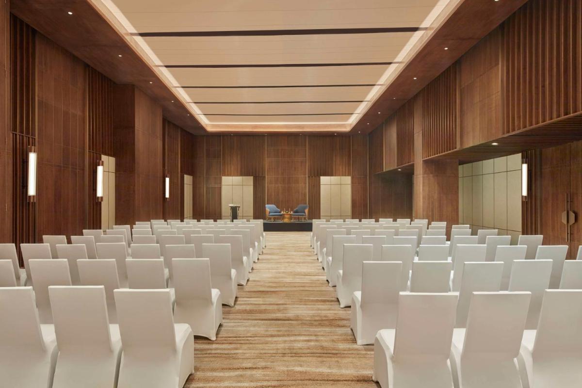 an empty lecture hall with white chairs and wooden walls at Hilton Gurugram Baani City Centre in Gurgaon
