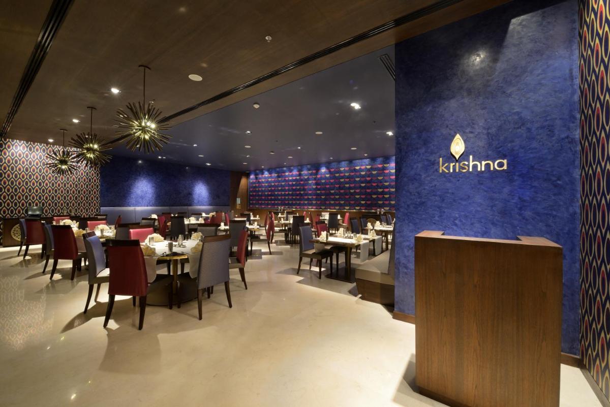 a restaurant with tables and chairs and a blue wall at Marasa Sarovar Premiere in Tirupati