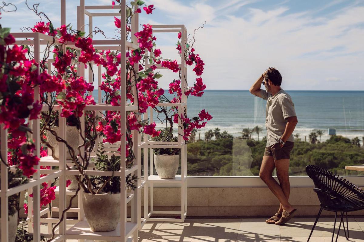 un hombre parado en un balcón con vistas al océano en Iberostar Selection Llaut Palma- Adults Only, en Playa de Palma