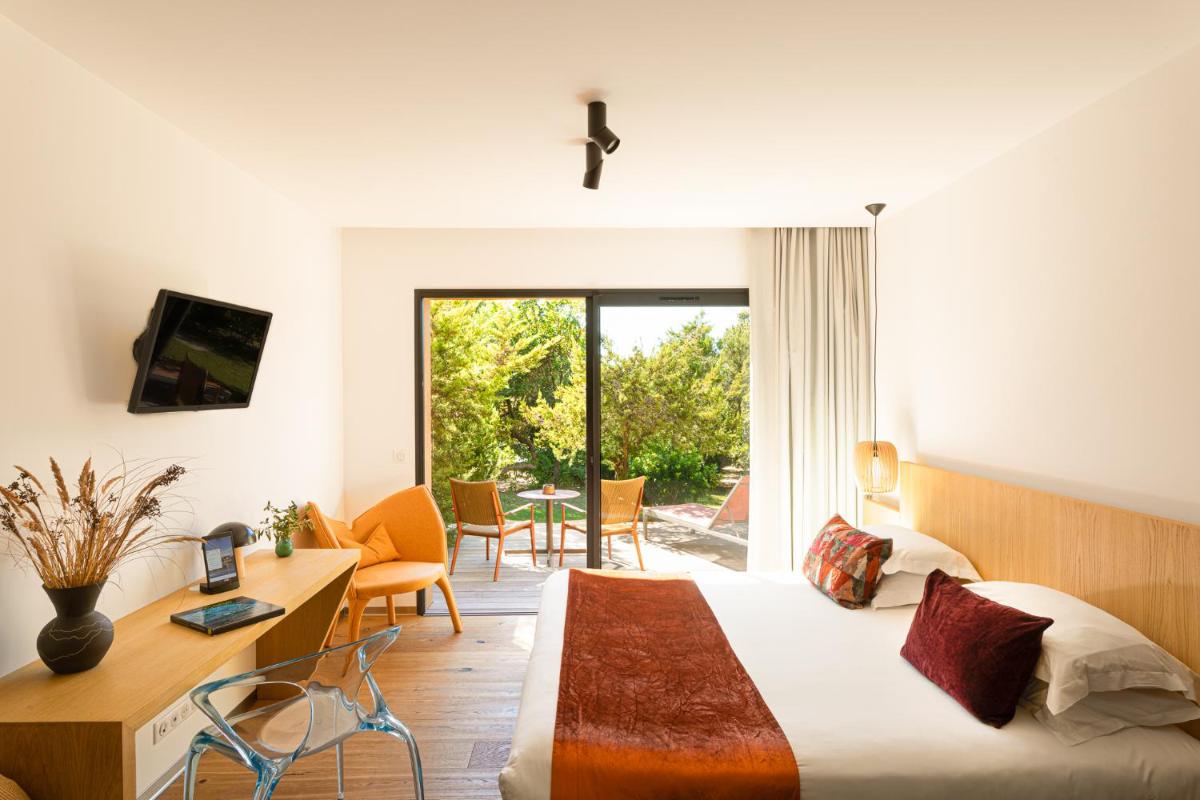 une chambre avec un lit, un bureau et une table dans l'établissement Hôtel & Spa Version Maquis Citadelle, à Bonifacio une chambre avec un lit, un bureau et une table dans l'établissement Hôtel & Spa Version Maquis Citadelle, à Bonifacio