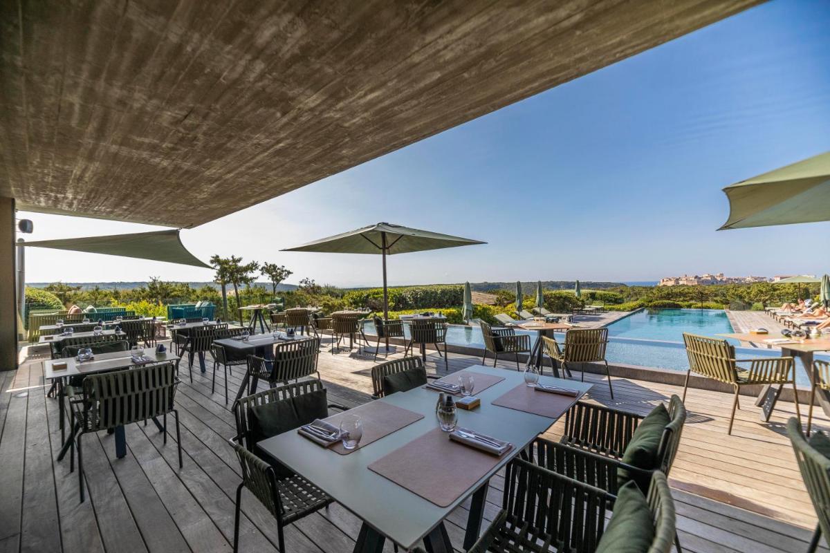 un restaurant en plein air avec des tables et des chaises ainsi qu'une piscine dans l'établissement Hôtel & Spa Version Maquis Citadelle, à Bonifacio