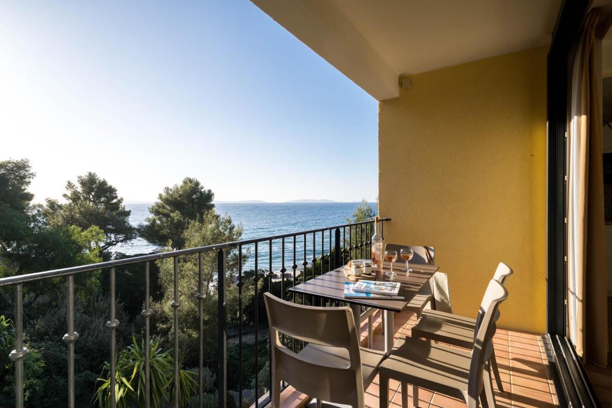 un balcon avec une table et des chaises et l'océan dans l'établissement La Résidence du Bailli, à Rayol-Canadel-sur-Mer