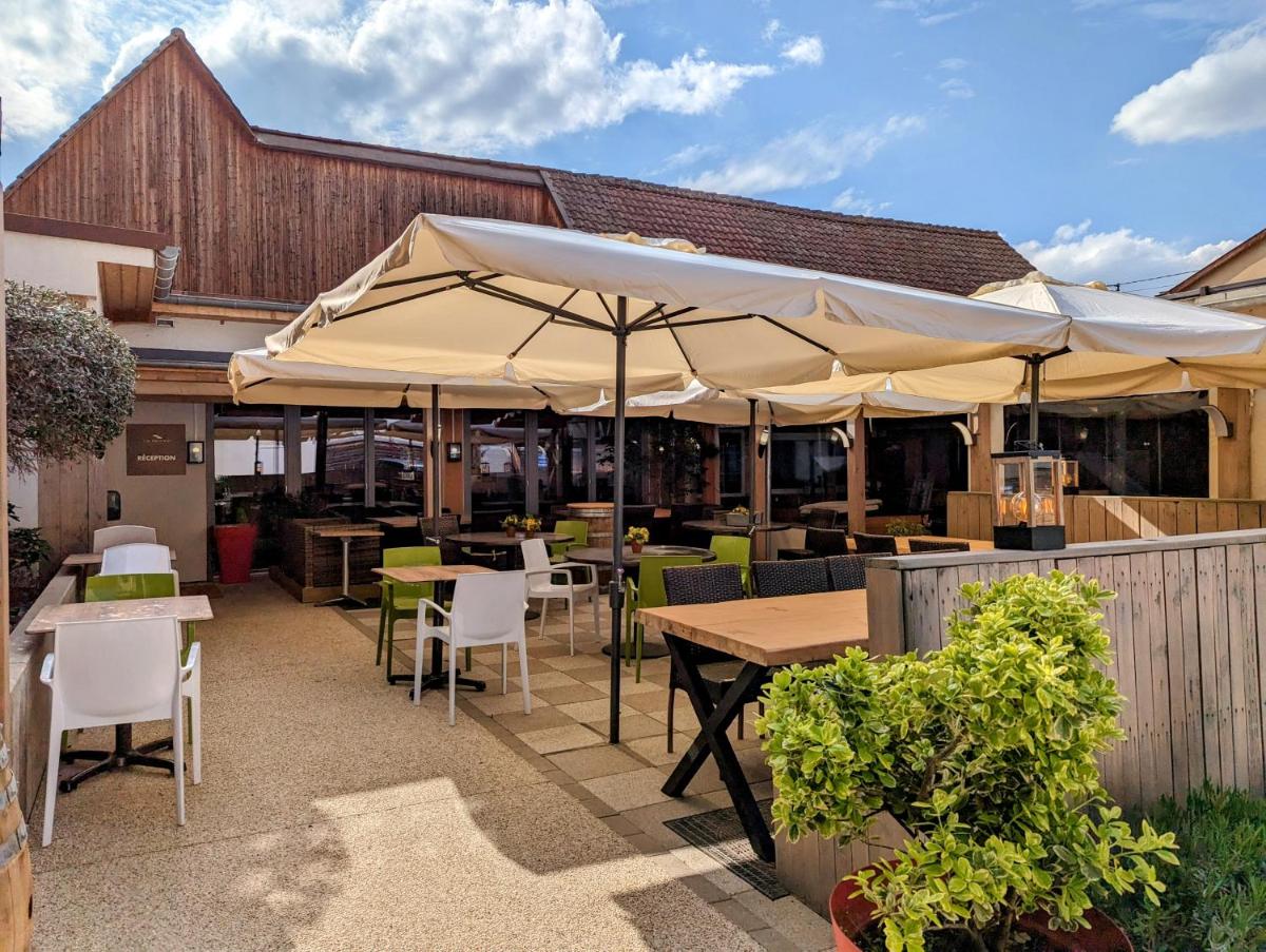 une terrasse extérieure avec tables, chaises et parasols dans l'établissement Hôtel Le Dormeur, à Dorlisheim
